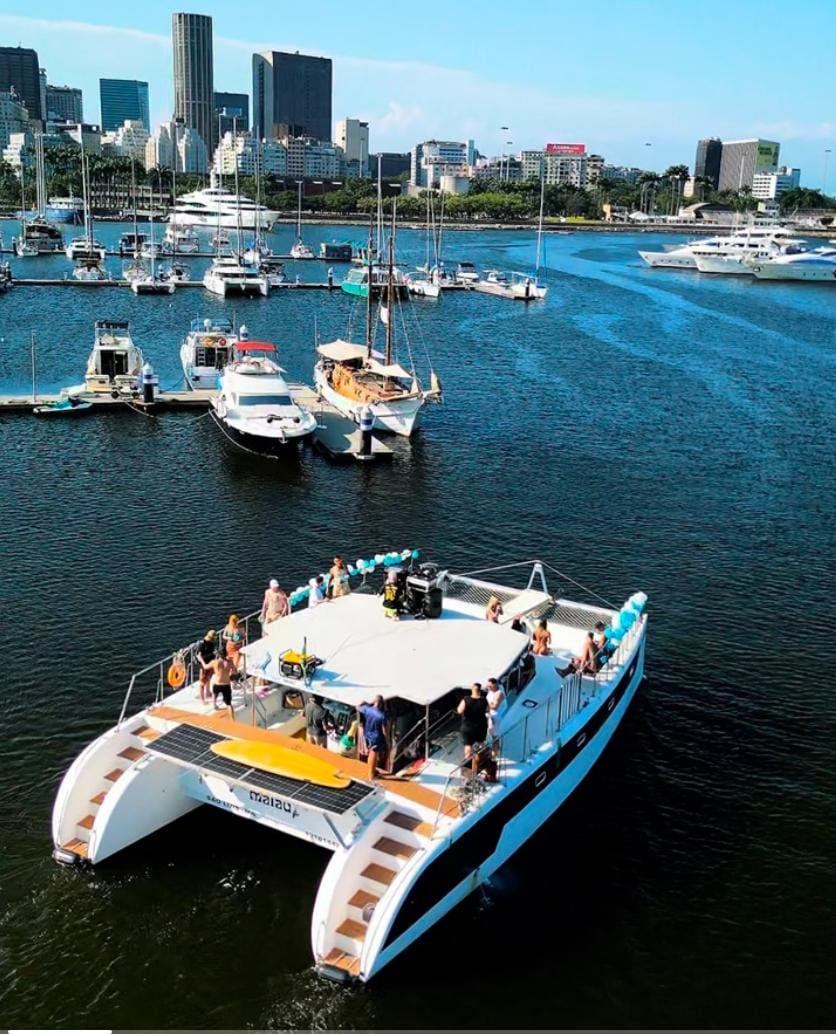 Grupo de fiesta a bordo de un catamarán en Río de Janeiro, con globos, música y la ciudad de fondo