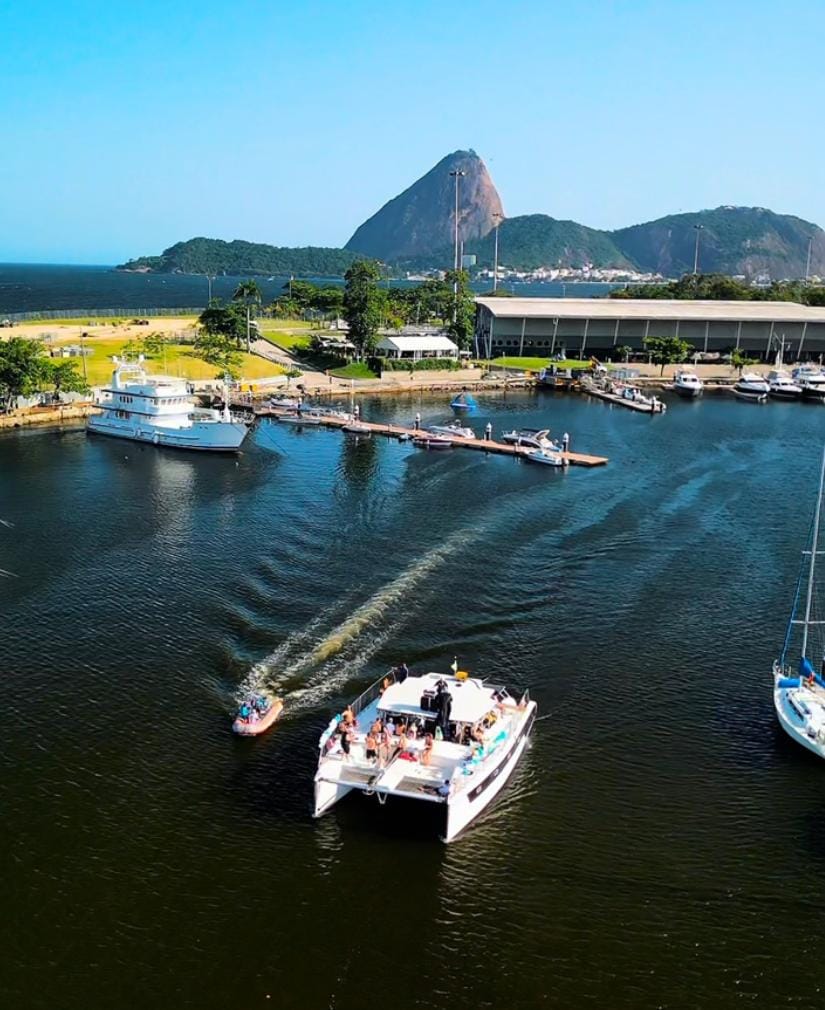 Vista aérea de un catamarán navegando en la Marina da Glória de Río de Janeiro con el Pão de Açúcar de fondo