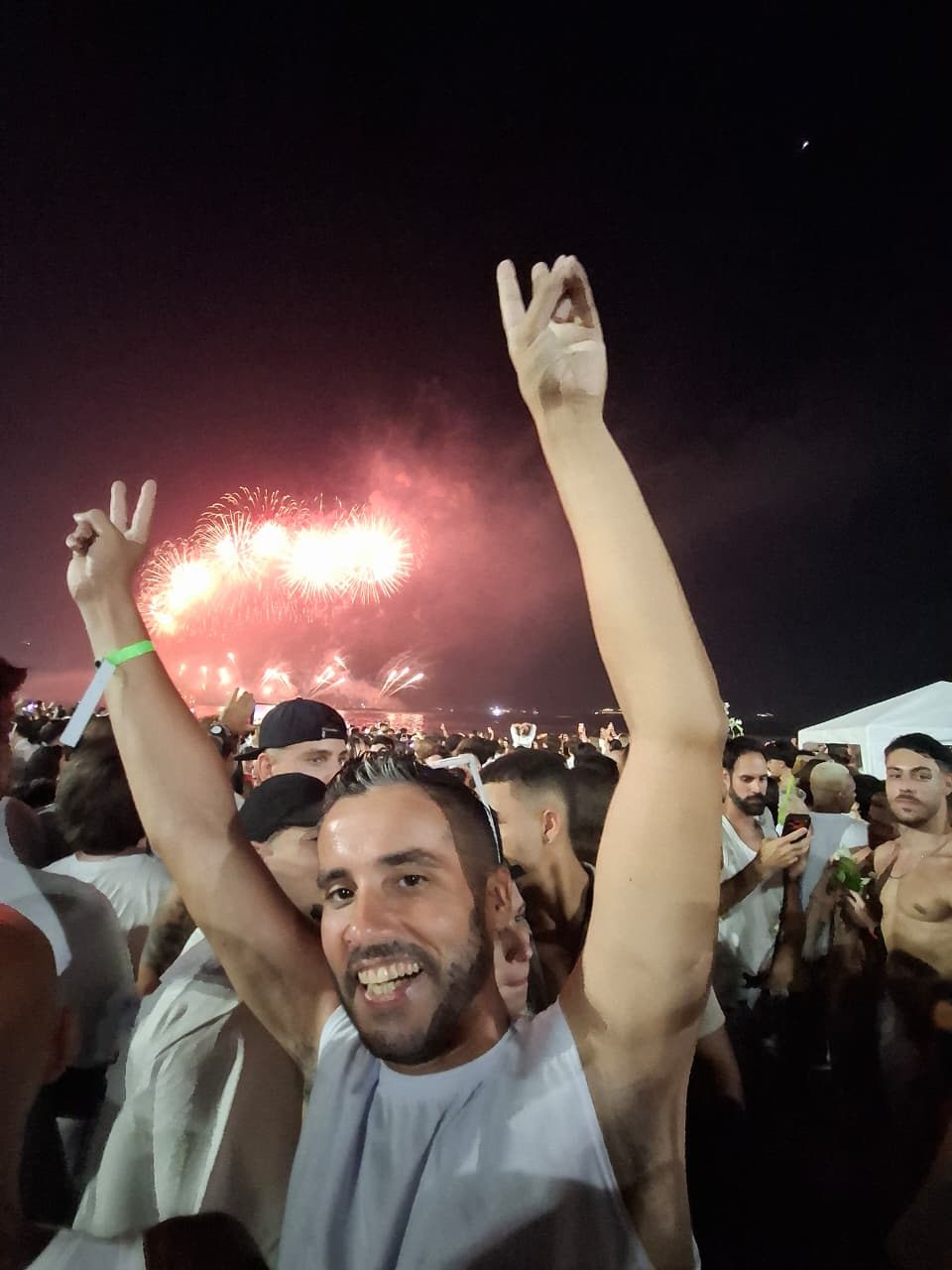 Camilo celebrando con los fuegos artificiales del Réveillon de Copacabana de fondo, todos de blanco