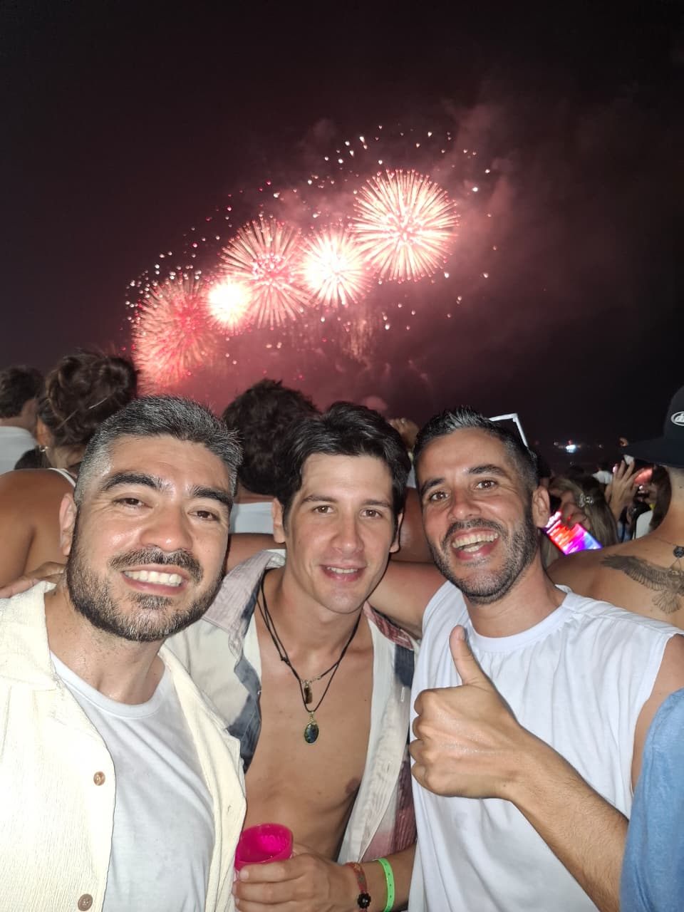 Grupo de amigos con los fuegos artificiales del Año Nuevo de Copacabana de fondo